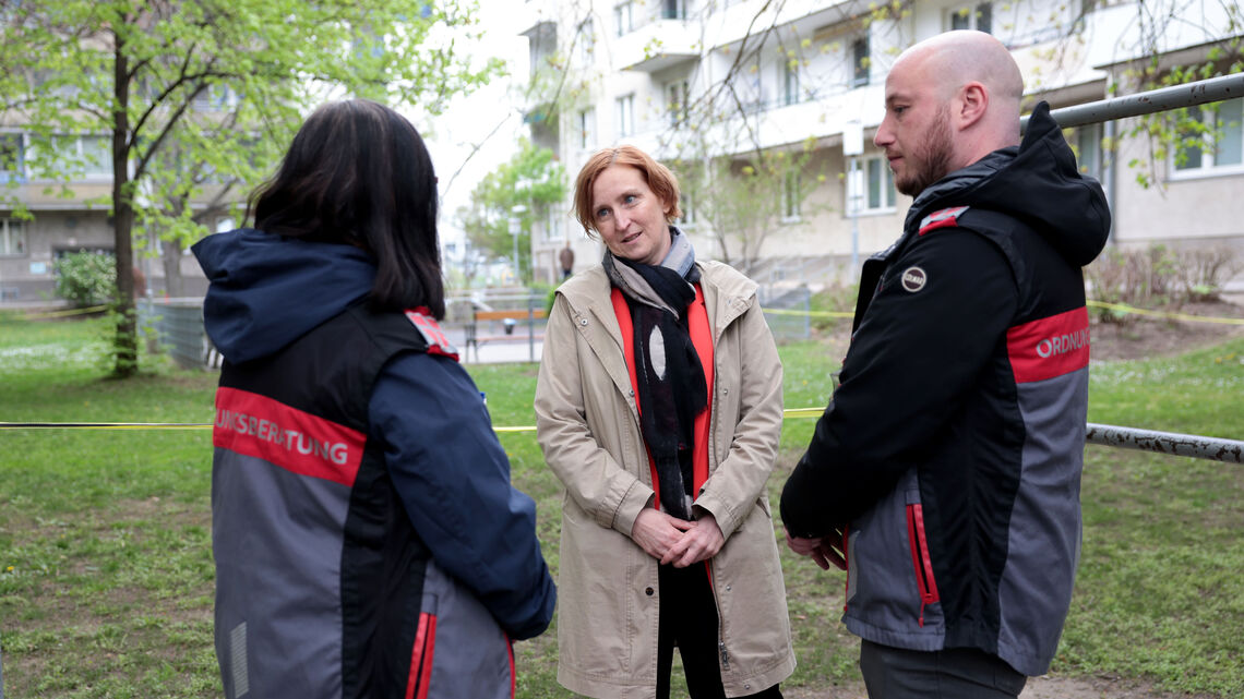 Zwei Ordnungsberater*innen von hinten im Gespräch mit Elke Hanel-Torsch, der Wohnbaustadträtin.